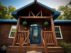 A wooden cabin with a porch, a decorative door, and a blue roof.