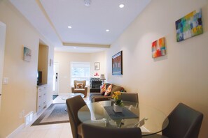 A modern living room with a glass dining table, a sofa, and a fireplace.