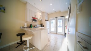 A modern kitchen with a central island, bar stools, a microwave, and a refrigerator. - Promo Holidays!2Beds2Bath6PPL Banff Close Gem in Mountain View Townhouse (Harvie Heights)