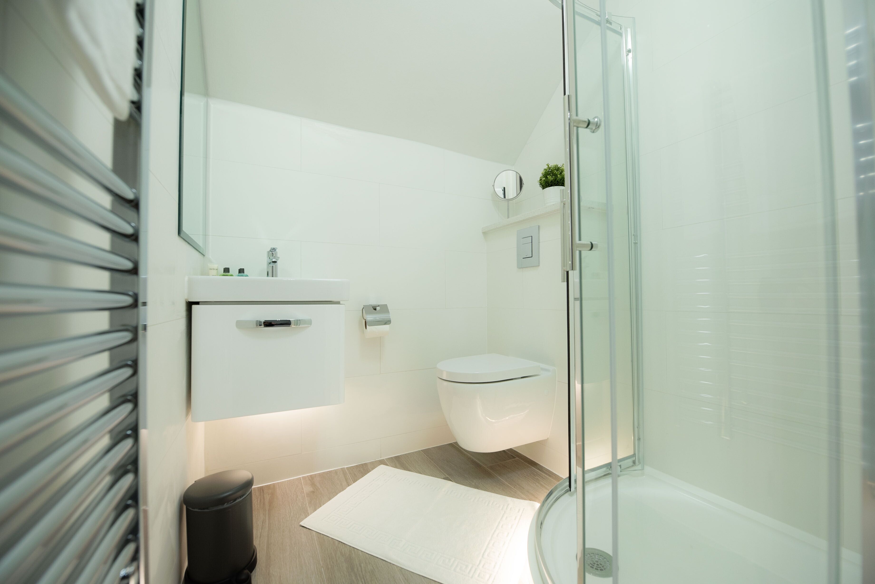 Un baño moderno con cabina de ducha de vidrio, un lavabo blanco y un inodoro.