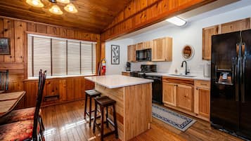 Une cuisine avec des meubles en bois, un îlot central et un réfrigérateur noir.