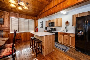 Une cuisine avec des meubles en bois, un îlot central et un réfrigérateur noir.