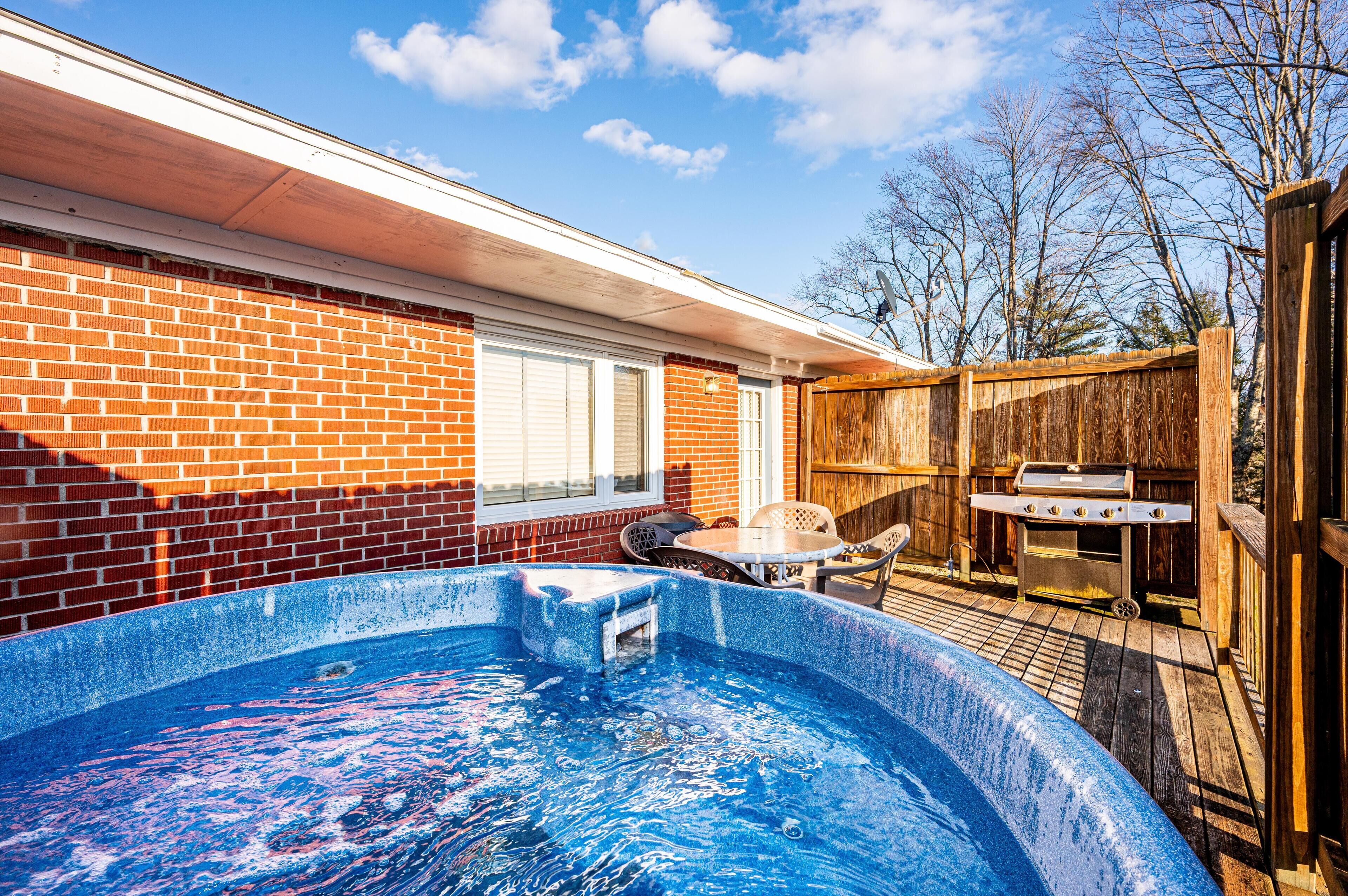 Un jardin avec une piscine, un barbecue et une terrasse en bois.