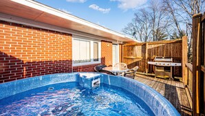 Ein Garten mit Schwimmbad, Grill und einer Holzterrasse.
