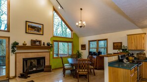 A spacious kitchen with a fireplace, wooden cabinets, and large windows. - Private Chalet Near State Forest | Game Room, Fire Pit & Views (Unionville)