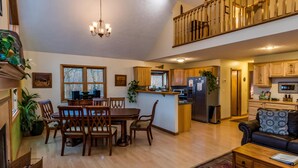 A spacious living area with a dining table, chairs, a sofa, and a kitchen in the background. - Private Chalet Near State Forest | Game Room, Fire Pit & Views (Unionville)