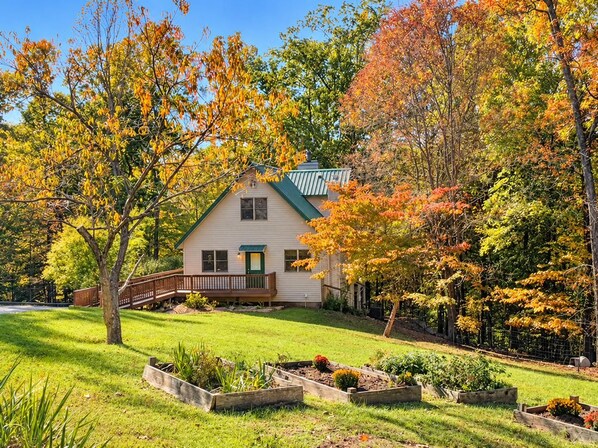 A house with a green roof, surrounded by a well-maintained lawn and garden beds.