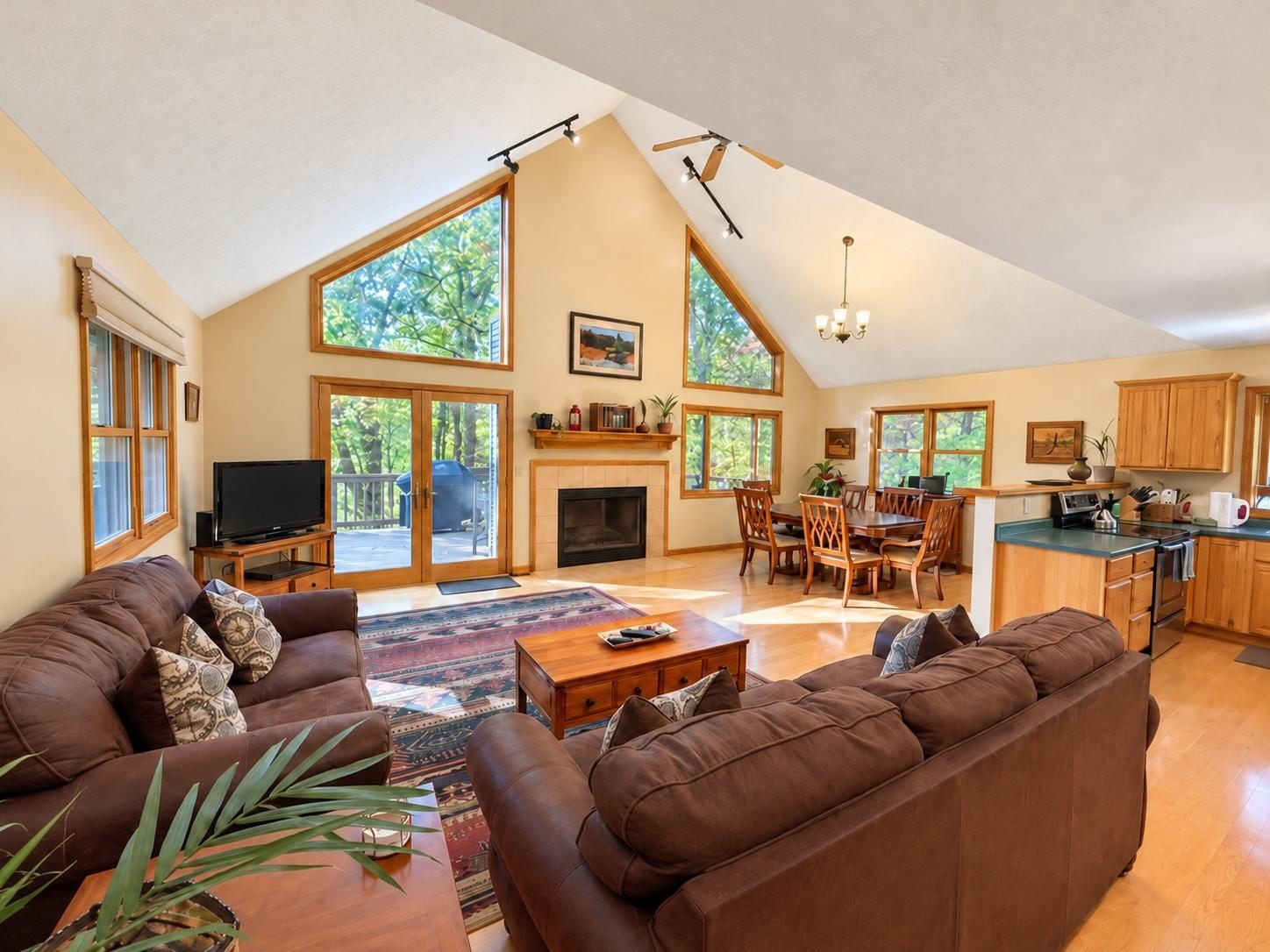 A spacious living area with a fireplace, large windows, and a kitchen with wooden cabinets.