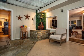A cozy interior with a stone fireplace, a wooden chair, and a wall adorned with stars and greenery. - Private Country Resort | Pool, Hot Tub & 5 Wooded Acres (Morgantown)