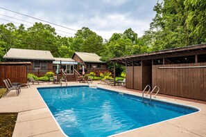 A rectangular swimming pool with a wooden deck and lounge chairs.