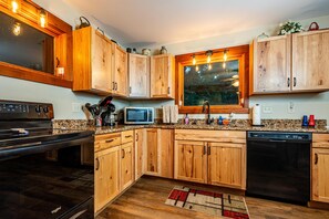 Une cuisine avec des meubles de rangement en bois, un four à micro-ondes, une cuisinière et un lave-vaisselle.