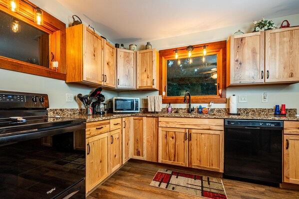 A kitchen with wooden cabinets, a microwave, a stove, and a dishwasher.