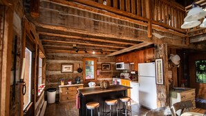 L’intérieur d’un chalet rustique comprend un bar en bois, des tabourets, une cuisine équipée et un coin repas.