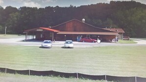 A large building with a red roof, a covered parking area, and a grassy field in front. - Cowboy Guest Suite | Near Trails, Events & Music Barn 1BR, 1BA (Nashville)
