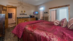 A bedroom with a large bed, a wooden dresser, a television, and a window with curtains. - Cowboy Guest Suite | Near Trails, Events & Music Barn 1BR, 1BA (Nashville)