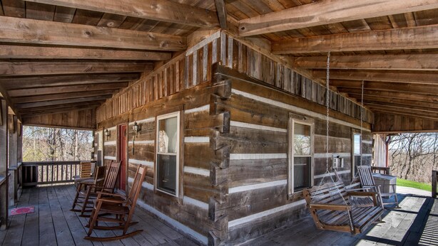 A log cabin with a porch, rocking chairs, and a hanging chair. - Secluded Log Cabin | Hot Tub, Fireplace & Near Nashville 2BR, 1.5BA (Nashville)