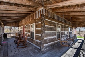 A log cabin with a porch, rocking chairs, and a hanging chair. - Secluded Log Cabin | Hot Tub, Fireplace & Near Nashville 2BR, 1.5BA (Nashville)
