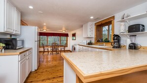 A kitchen with white cabinets, a wooden countertop, and a dining area with chairs and a table. - Hilltop Cabin 2 Miles to Nashville | Hot Tub & Valley Views 2BR, 2BA (Nashville)