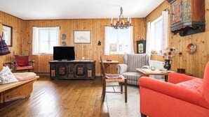 A wooden-paneled room with a television, a sofa, a chair, and a table.