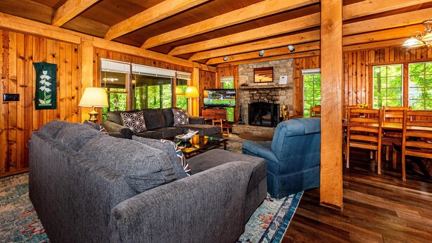 L’intérieur d’un chalet en bois comprend une cheminée, un téléviseur et un coin repas.
