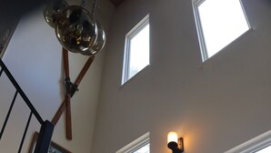 A staircase with black railings and wooden steps, leading to a landing with a wall-mounted light fixture and a framed picture.