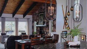 A dining area with a wooden table and chairs, a stone wall, and a fireplace.