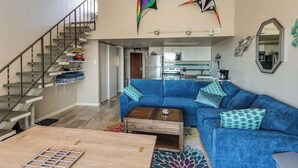 Ein modernes Wohnzimmer mit einem blauen Sofa, einem Holztisch und einer Treppe.