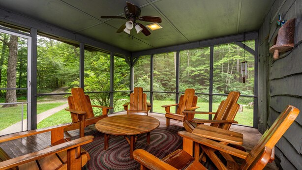 A covered outdoor seating area with wooden furniture and a ceiling fan. - 85-Acre Family Cabin | Sleeps 12, Hot Tub & Near Nashville 4BR, 2 BA (Nashville)