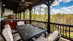A covered outdoor patio with a table and chairs, a ceiling fan, and a view of trees and hills. - Mountain View Log Cabin | Hot Tub, 3 Kings & Game Room 3BR, 3BA (Nashville)