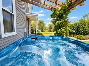 A hot tub in a backyard with a house and greenery in the background. - Farmhouse Retreat 2 Miles to Nashville | Hot Tub 3BR, 2BA (Nashville)