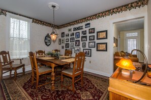 A dining room with a wooden table and chairs, surrounded by framed family photos on the walls. - Farmhouse Retreat 2 Miles to Nashville | Hot Tub 3BR, 2BA (Nashville)