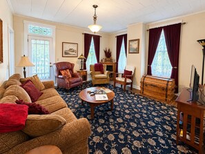 A traditional living room with a patterned carpet, leather armchairs, a wooden coffee table, and a vintage trunk.