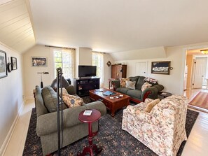 A living room with a sofa, armchair, coffee table, and a television. - Farmhouse Retreat 2 Miles to Nashville | Hot Tub 3BR, 2BA (Nashville)