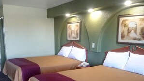 Ein Hotelzimmer mit zwei Betten, jeweils mit Kopfteil, Telefon und einem gerahmten Bild an der Wand.