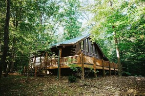 A wooden cabin with a porch, surrounded by dense forest. - Hilltop Hideaway | Hot Tub, Views & Wraparound Porch 3BR, 2.5BA (Nashville)