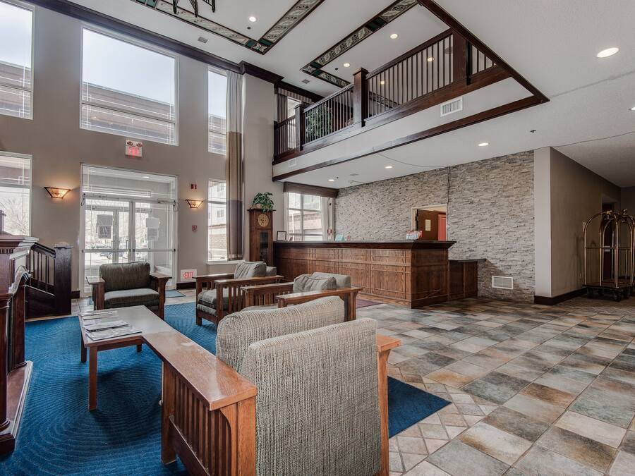 Eine großzügige Lobby mit hoher Decke, einer Treppe und einer Sitzecke mit Holzmöbeln.