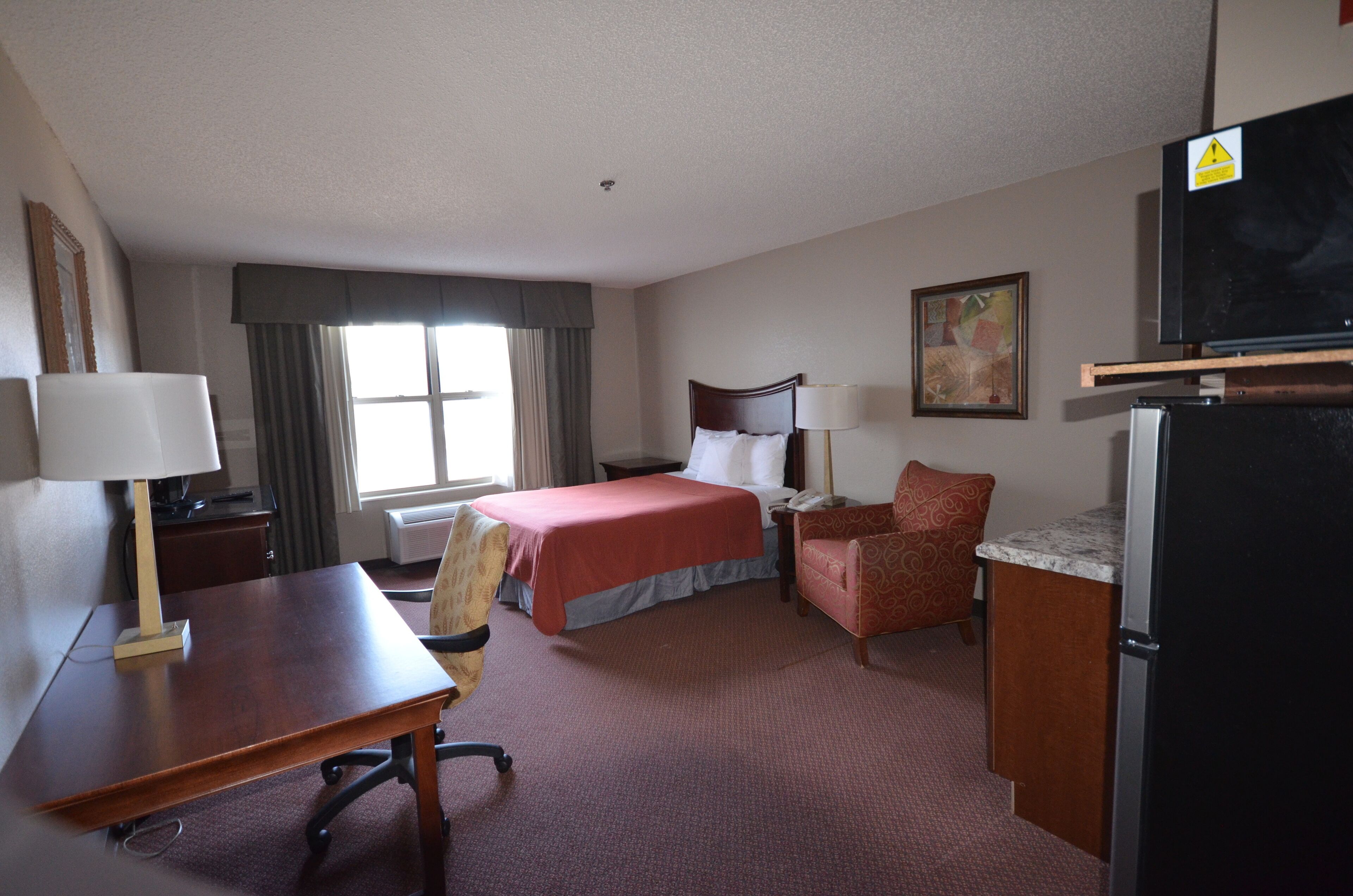 Habitación de hotel con cama, escritorio, silla y televisor.