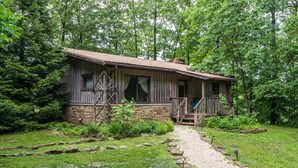 Eine rustikale Holzhütte mit Stein Fundament und einer Veranda.