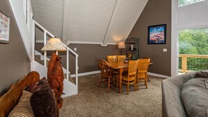 A dining area with a wooden table and chairs, a lamp, and a bear sculpture. - Cabin w/ Pond, Hot Tub & Pool Table | Family-Friendly Retreat 3BR, 2BA (Nashville)