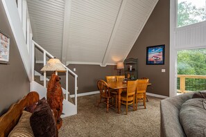 A dining area with a wooden table and chairs, a lamp, and a bear sculpture. - Cabin w/ Pond, Hot Tub & Pool Table | Family-Friendly Retreat 3BR, 2BA (Nashville)