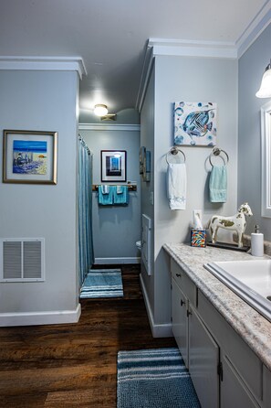 Une salle de bain avec un plancher en bois, un lavabo, un miroir et un porte-serviettes.