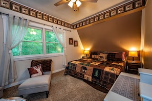 A bedroom with a large bed, a chair, a desk, and a window with curtains. - Cabin w/ Pond, Hot Tub & Pool Table | Family-Friendly Retreat 3BR, 2BA (Nashville)