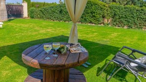 A round wooden table with two glasses of white wine, a small plate with food, and a pair of sunglasses. - Noa de Marchena by Ruralidays (Seville)