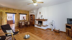 A spacious living room with a fireplace, dining area, and a TV stand. - Noa de Marchena by Ruralidays (Seville)