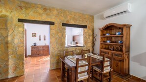 A dining area with a stone wall, wooden furniture, and a built-in cabinet with dishes. - Noa de Marchena by Ruralidays (Seville)