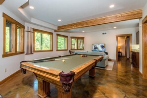 A pool room with a pool table, seating area, and a television.