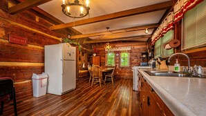 A rustic wooden cabin interior with a dining area, a refrigerator, and a sink. - 2 BA, (1 is a loft), 1 BA Log Cabin (Morgantown)