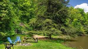 A serene lakeside setting with a picnic table, blue Adirondack chairs, and a wooden deck. - 2 BA, (1 is a loft), 1 BA Log Cabin (Morgantown)