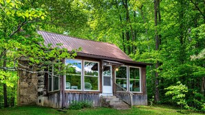 A rustic cabin with a stone foundation, large windows, and a wooden porch. - 2 BA, (1 is a loft), 1 BA Log Cabin (Morgantown)