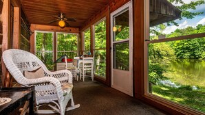 A covered porch with wicker rocking chairs, a table, and a view of a lake. - 2 BA, (1 is a loft), 1 BA Log Cabin (Morgantown)